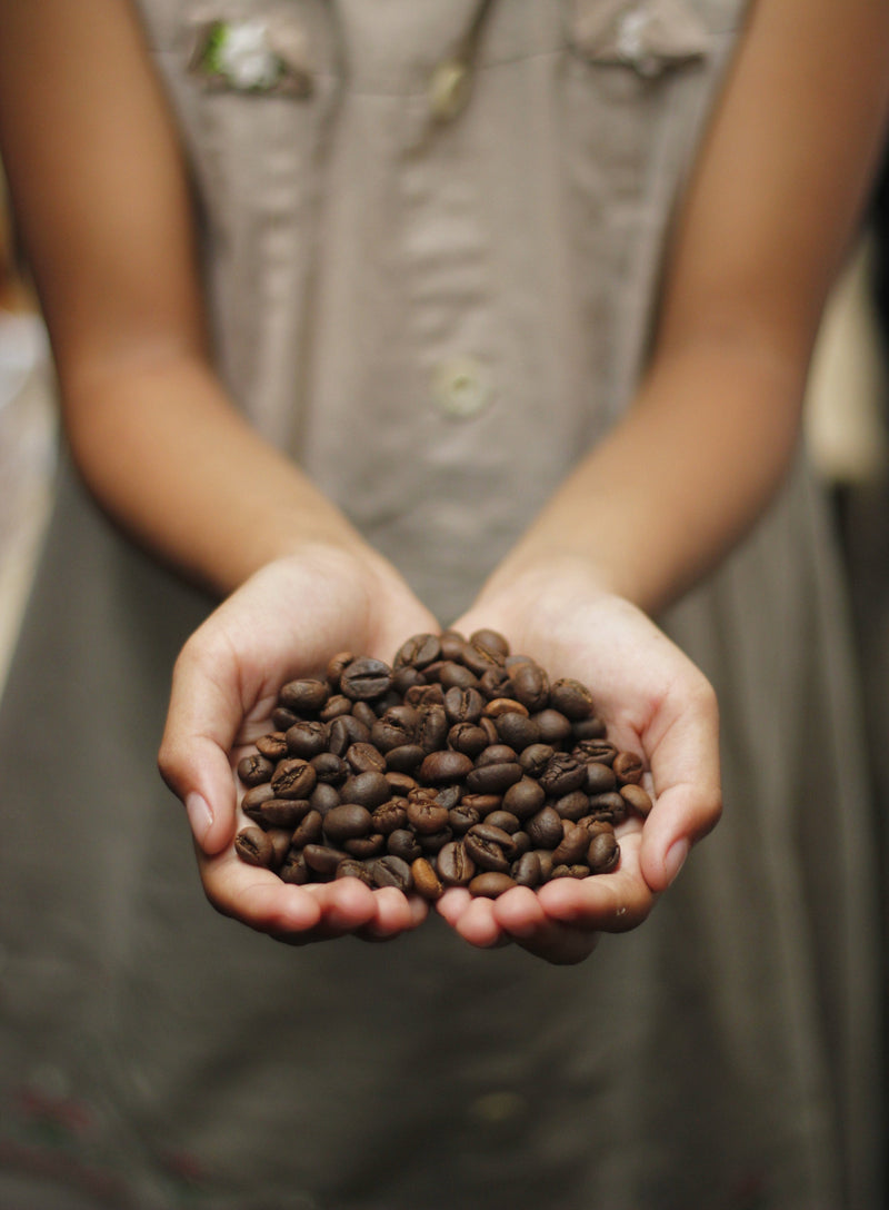 A woman holding coffee beans in her hands.