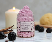 Pink whipped soap in a jar with blackberries and vanilla beans on a neutral background