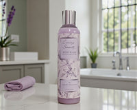 Body wash bottle labeled 'Evening Serenity' on a bathroom counter with a bathtub and plants in the background.
