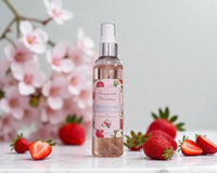 Bottle of Honeysuckle Strawberry Fragrance Mist with strawberries and cherry blossoms in the background