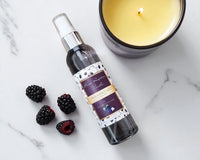 Bottle of blackberry raspberry vanilla fragrance mist with a candle and blackberries on a marble surface