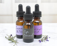 Three bottles of car diffuser refill bottles on a white marble surface.