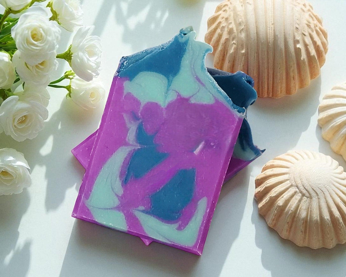 Colorful soap bar with a marbled design on a white surface with seashells and white flowers.