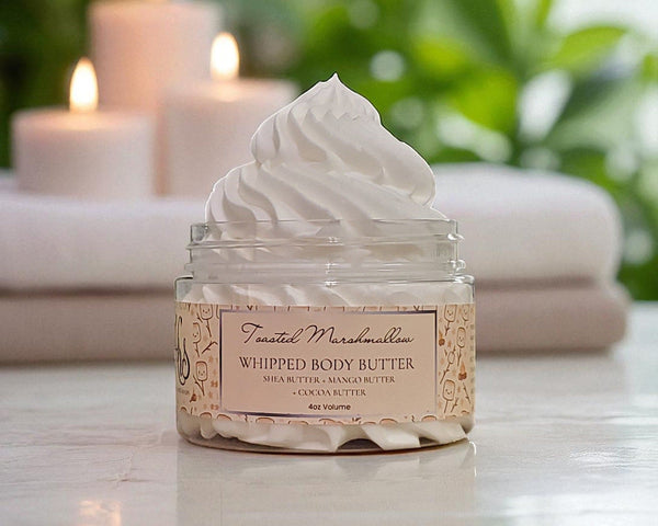 Jar of whipped body butter with a label on a surface with candles in the background