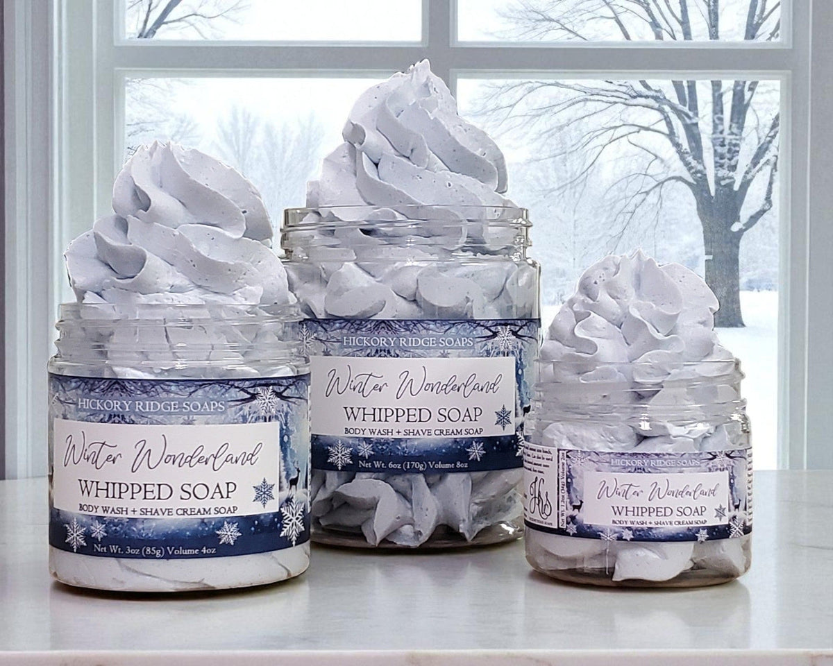 Three jars of 'Winter Wonderland' whipped soap on a windowsill with a snowy outdoor view.